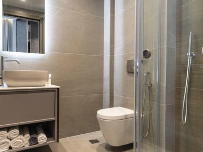 Nowoczesna łazienka z szklaną prysznicem, toaletą i umywalką z ręcznikami.