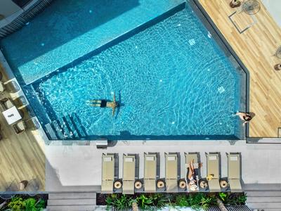 Dachpool mit Sonnenliegen und Personen auf Holzdeck und im Wasser, helle Atmosphäre
