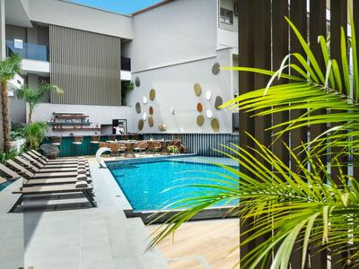 Moderner Außenpool mit Liegestühlen und Pflanzen in einem Hotelbereich.