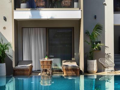 Modernes Hotelzimmer mit Doppelbetten direkt am Pool und Balkon darüber.