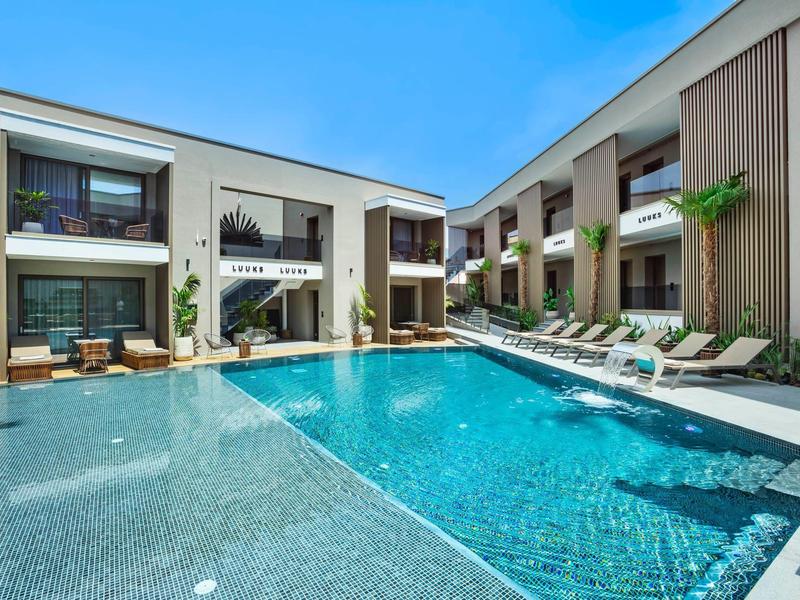 Nowoczesny hotelowy basen z leżakami i balkonami pod bezchmurnym niebem