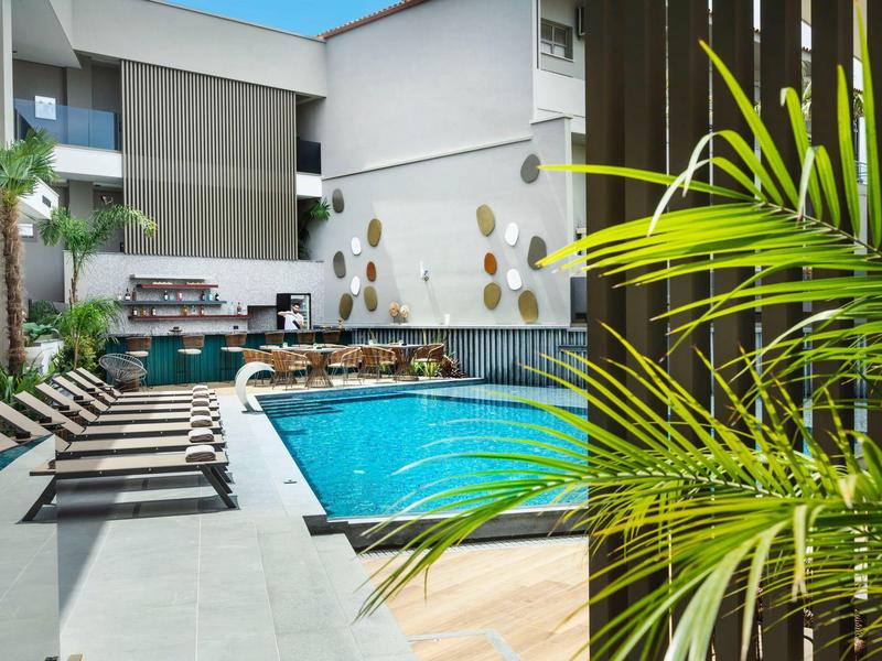 Nowoczesny basen na zewnątrz z leżakami i zielenią w hotelu.