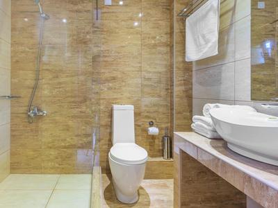 Clean, modern bathroom with toilet, sink, and walk-in shower with glass panel.