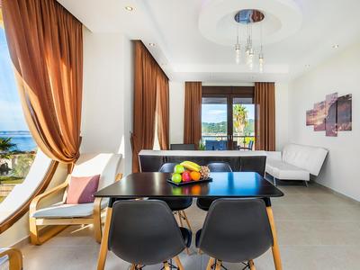 Salon lumineux avec coin repas, mobilier moderne et vue sur la mer à travers les fenêtres.