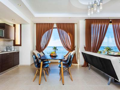 Modern dining and living area with large windows showing sea view.