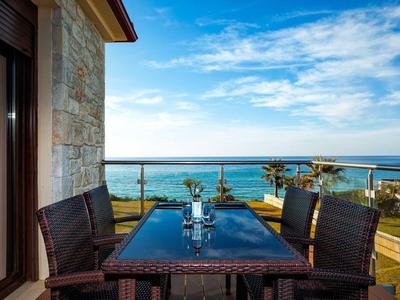 Terrace with dining table and chairs overlooking the sea on a sunny day