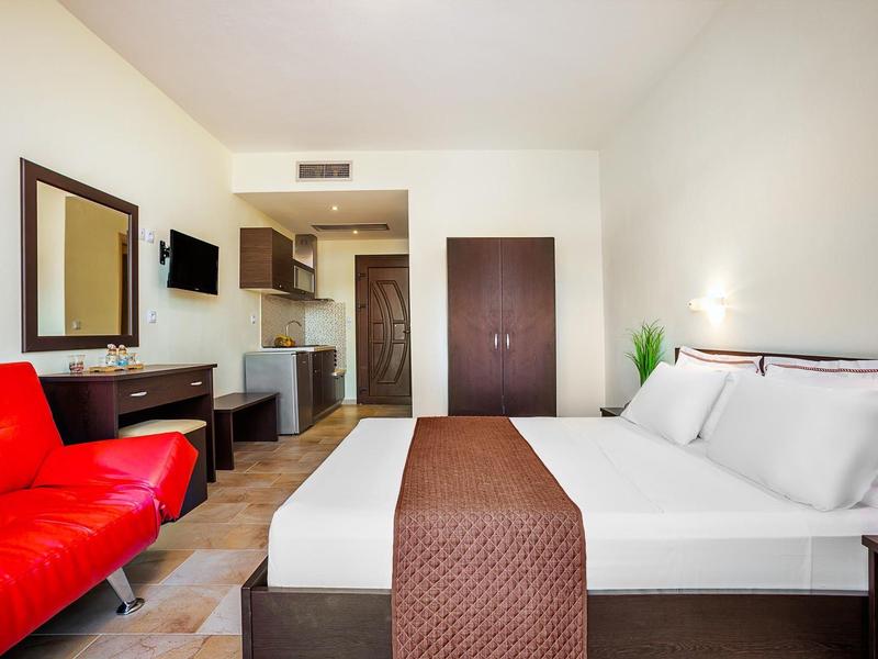 Modern hotel room with large bed, red sofa, and desk.
