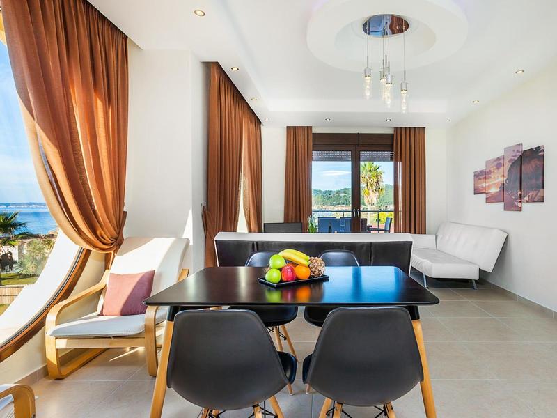 Bright dining area with garden and sea view, modern furniture, and brown curtains.