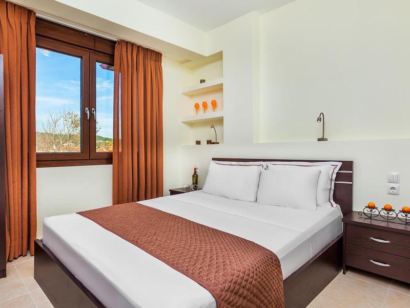 Bright hotel room with double bed, nightstand, and large window with brown curtains.