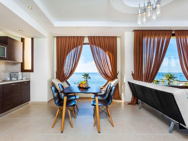 Modern dining and living area with large windows showing sea view.