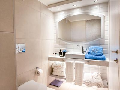 Kleines Badezimmer mit weißem Waschbecken, großem Spiegel, Handtüchern und sanfter Beleuchtung.