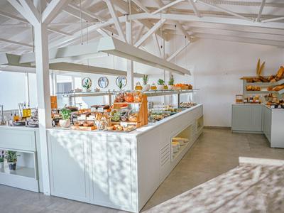 Helle Bäckerei mit modernen weißen Regalen und vielfältigem Brot- und Gebäckangebot.