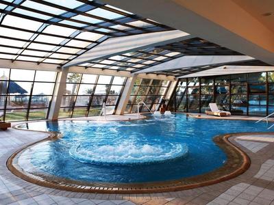 Innenpool mit Whirlpool in einem Hotel mit großer Glasdecke und Terrasse.