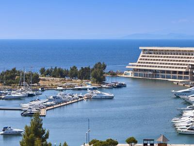 Hafen mit Yachten und modernes Hotelgebäude am Meer unter blauem Himmel.