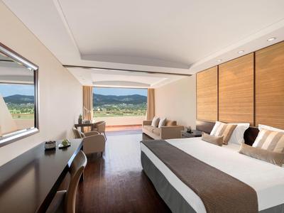 Helles Schlafzimmer mit großem Bett, Holzmöbeln und Panorama-Fenster mit Bergblick.