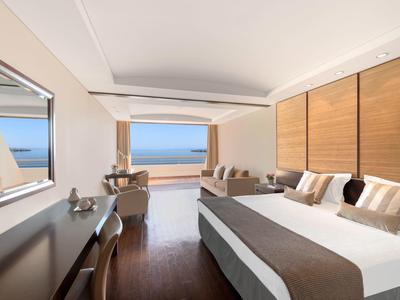 Modern eingerichtetes Hotelzimmer mit Doppelbett, großem Fensterblick auf das Meer und Holzdetails.