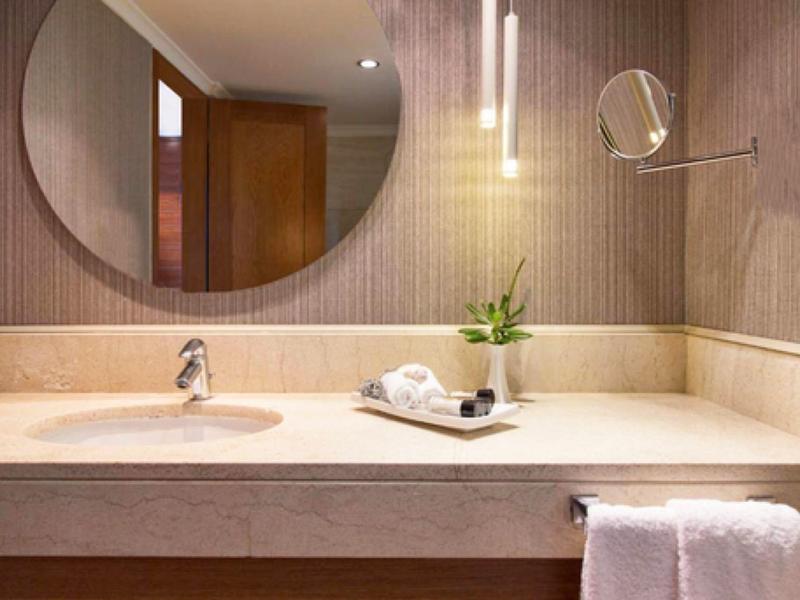 Moderner Badezimmerwaschtisch aus Marmor mit rundem Spiegel und dekorativer Pflanze.