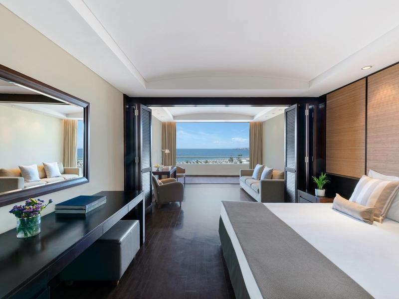 Helles Schlafzimmer mit großem Bett, Holzmöbeln und Panorama-Fenster mit Bergblick.