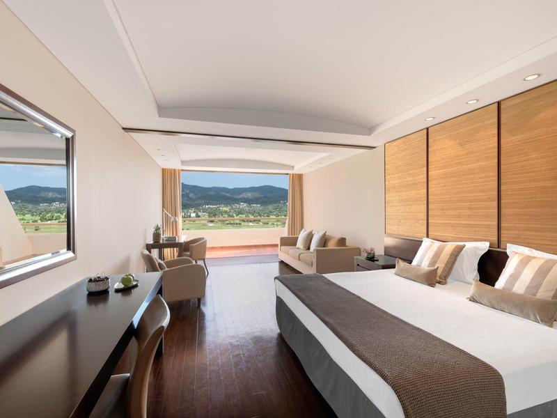 Helles Schlafzimmer mit großem Bett, Holzmöbeln und Panorama-Fenster mit Bergblick.