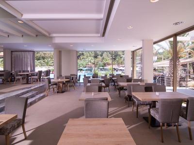 Helles und modernes Restaurant mit großen Fenstern und Blick auf einen Poolbereich.