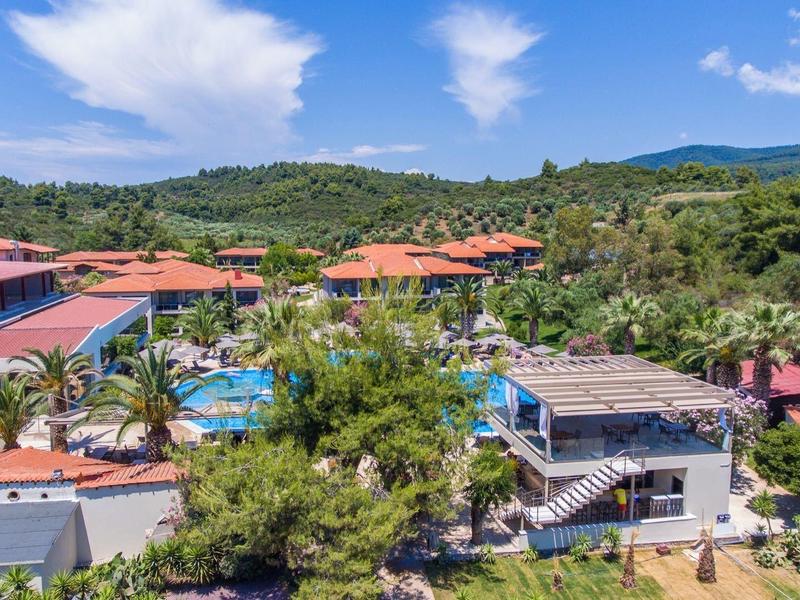 Landschaft mit Häusern, grünem Wald, Hügeln, blauen Pools und blauem Himmel mit Wolken.