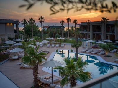Hotelpoolbereich mit Palmen und Sonnenliegen bei Sonnenuntergang