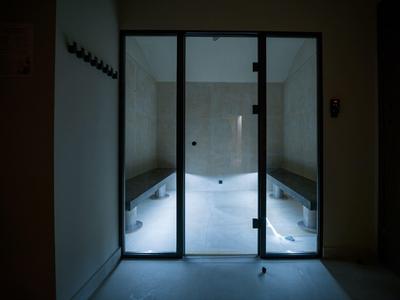 Lit, enclosed steam room with benches on both sides.