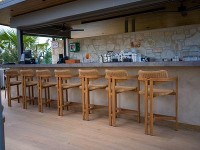 Open bar with wooden stools and stone wall background in a hotel setting.
