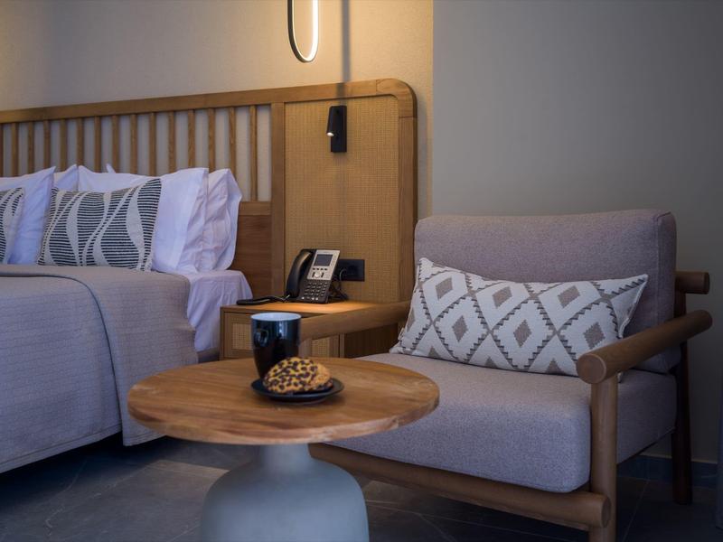 Cozy hotel room with modern armchair, wooden table, and decorative cushion.
