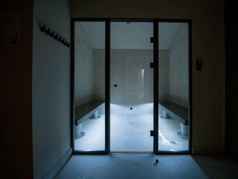 Lit, enclosed steam room with benches on both sides.