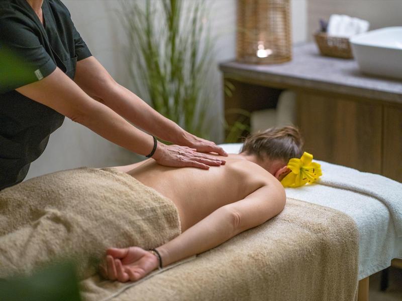 Woman receiving back massage in a relaxed spa setting with calming decor.