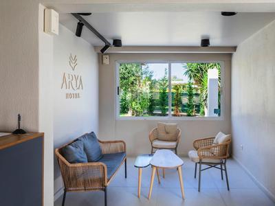 Světlý lounge kout s proutěnými křesly a stolky u velkého okna s výhledem na zahradu.