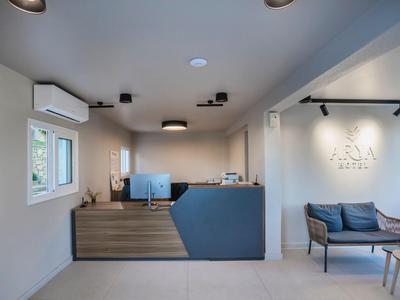 Moderner Empfangsbereich mit Holztheke, Sitzbereich mit Sofa und hellem, minimalistischem Design.