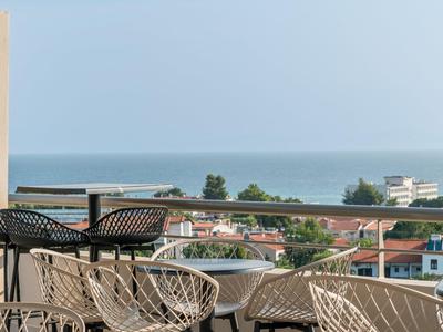 Balkon mit modernen Stühlen und Tisch mit Meerblick und Gebäuden im Hintergrund