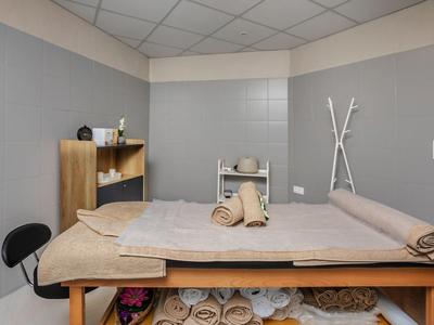 Modern spa room with massage table, gray walls, and white ceiling tiles.