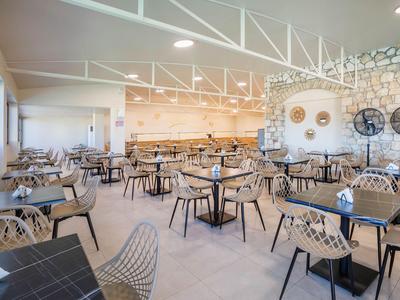 Bright, modern restaurant with tables and transparent chairs in a hotel.