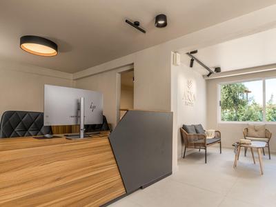 Moderní hotelová recepce s dřevěnou přepážkou a útulnou posezením u velkého okna.