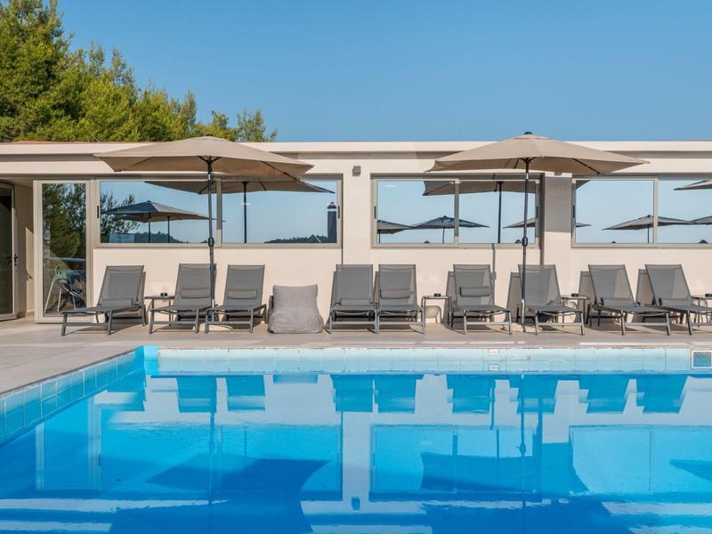 Moderní bazén s lehátky a slunečníky za jasného dne.