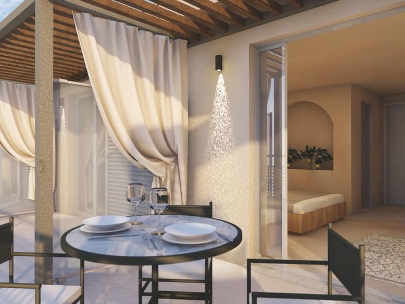 Moderní venkovní prostor hotelu s kulatými stoly, židlemi a poloprůhlednými závěsy.