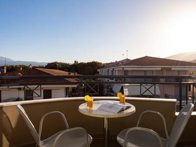 Balkon mit kleinem runden Tisch, zwei Gläsern Orangensaft und zwei Stühlen bei Sonnenuntergang.