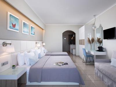 Modernes Hotelzimmer mit zwei Doppelbetten, grauen Decken, weißen Möbeln und Wandbildern.