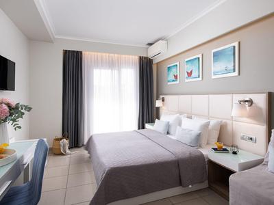 Helles Schlafzimmer mit Doppelbett, grauen Vorhängen, blauen Akzenten und moderner Deko an der Wand.