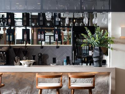 Moderner Hotelbarbereich mit Holzstühlen und Regalen mit Spirituosen in elegantem Ambiente