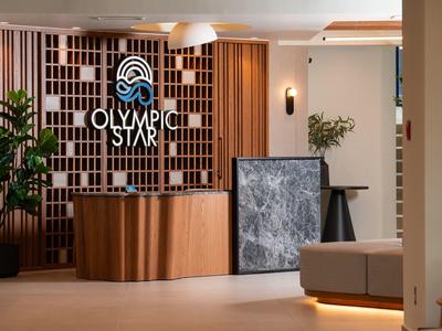 Moderner Empfangsbereich mit Holztheke, Wanddekor und Pflanzen in warmem, einladendem Ambiente.