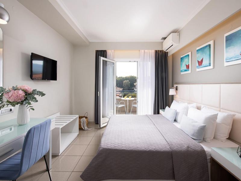 Helles, modernes Schlafzimmer mit Doppelbett, Schreibtisch, Balkon und Wandbildern in sanften Farben.