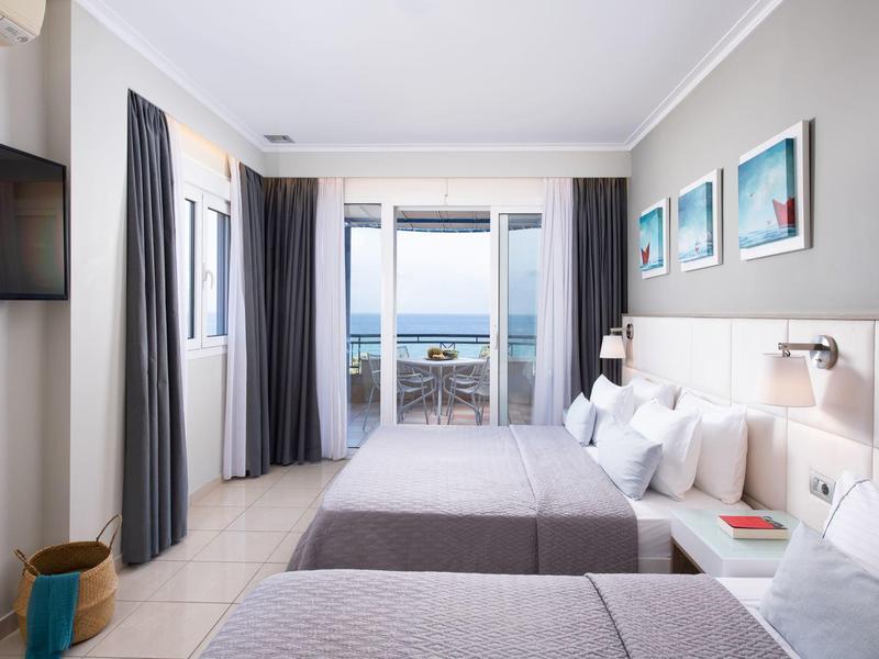 Modernes Doppelzimmer mit zwei Betten, Meerblick, Balkon, hellen Wänden und minimalistischer Einrichtung.