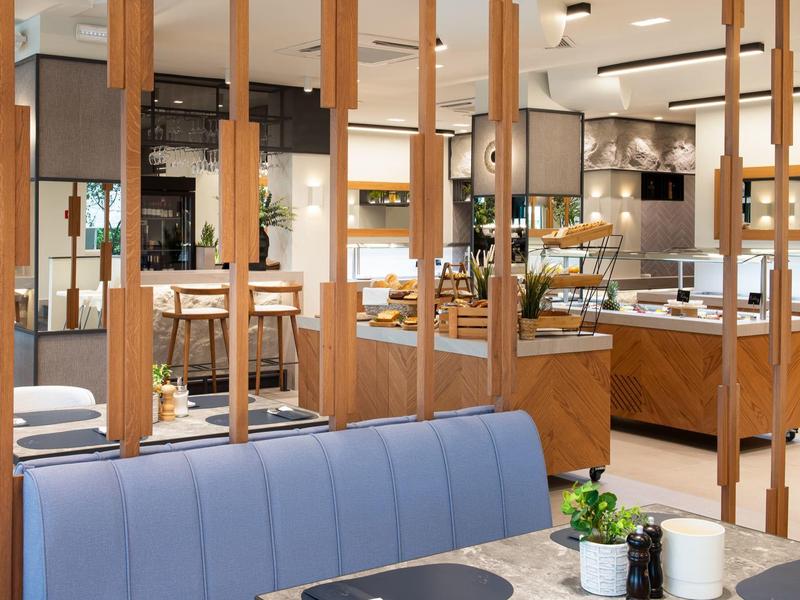 Modernes Restaurant mit blauen Polstersitzen, Holztrennwänden und stilvoller Beleuchtung.