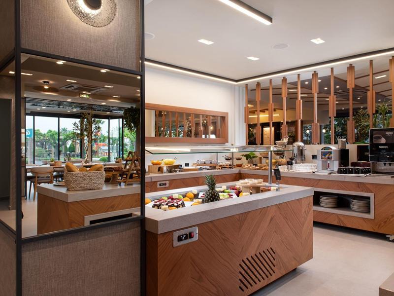 Modernes Hotelbuffet mit Obst, Gebäck und Getränken in hellem, stilvollem Raum.