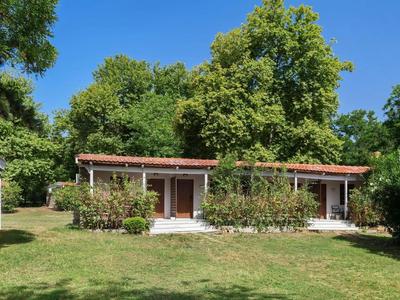 Petit bâtiment d'hôtel avec deux entrées latérales, entouré de verdure et de buissons sous un ciel bleu clair.