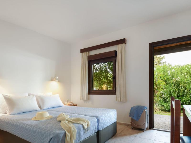 Bright hotel room with two single beds, desk, and garden view.